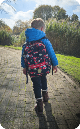The child carries the same backpack outdoors